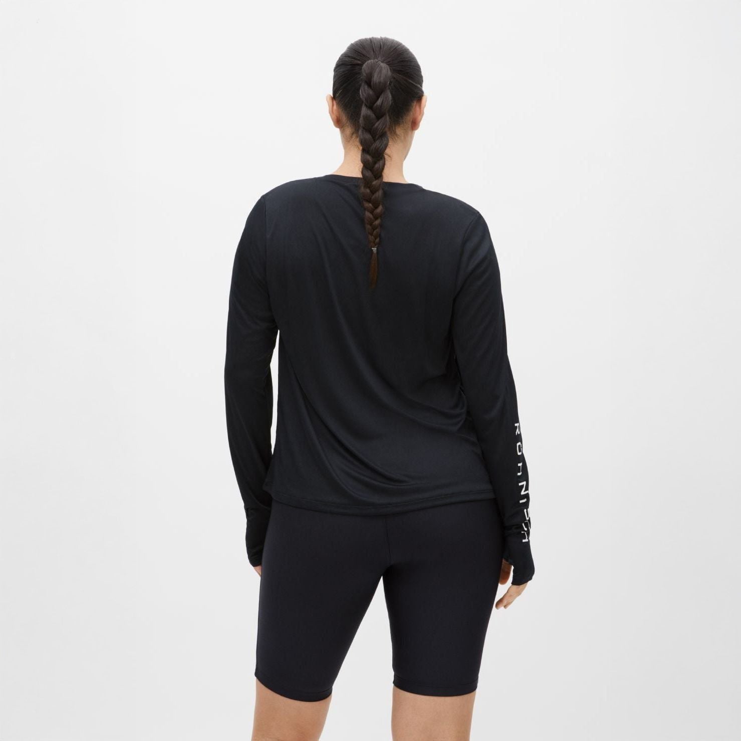 A person with a braid, wearing the Rohnisch Team Logo Long Sleeve and black shorts, stands facing away against a plain white background.