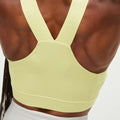 The back view showcases a muscular build wearing the Kay Sports Bra from Rohnisch, a yellow moisture-wicking sports bra with cross straps.
