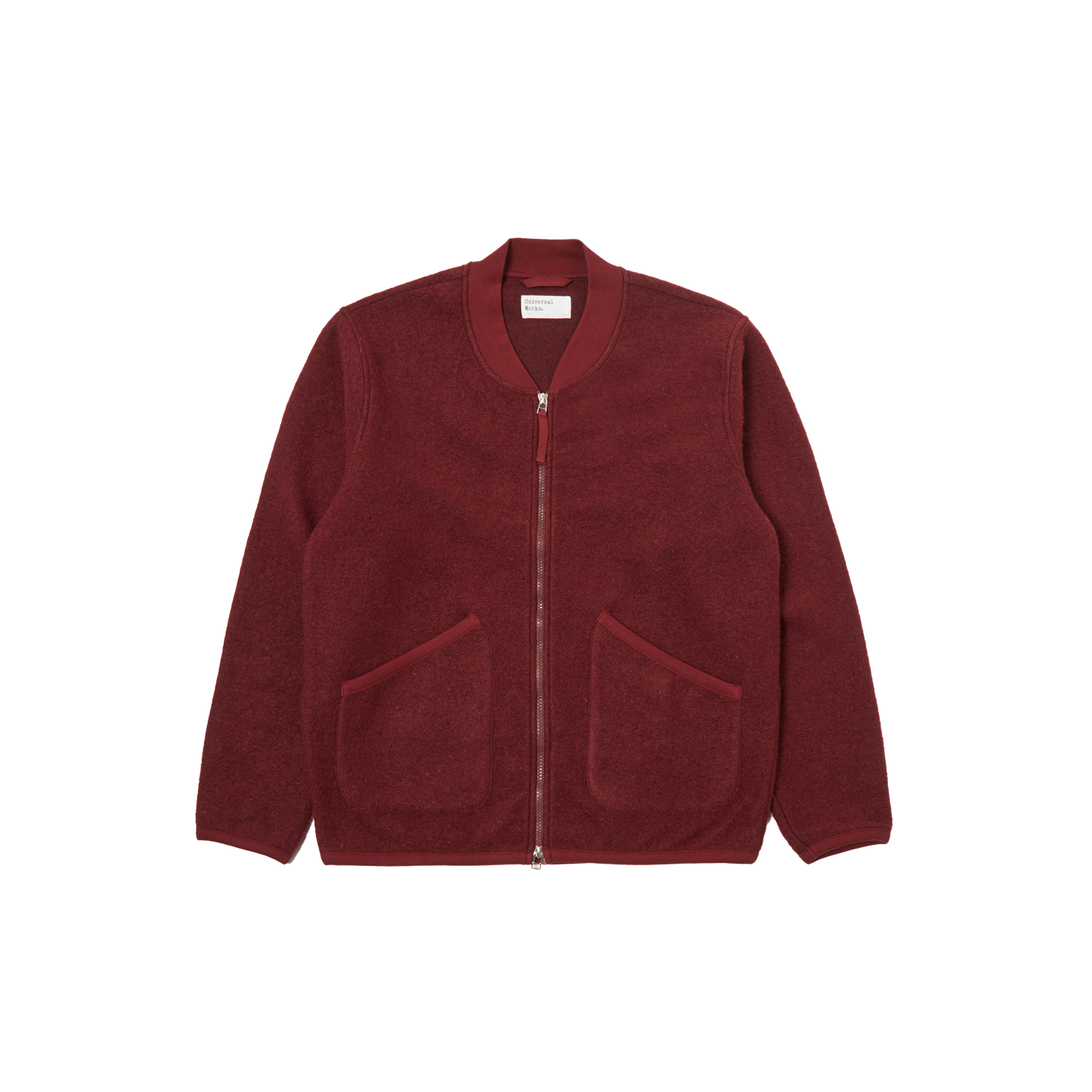 Universal Works introduces the Zip Bomber Fleece, a red jacket designed with a two-way zip and a simple collar. It is crafted in a regular fit and includes two front pockets for practicality.
